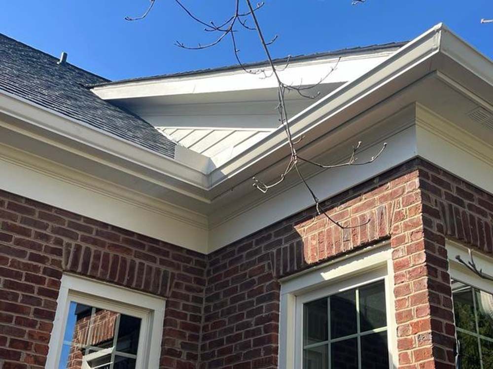 A brick house with a white gutter on the roof