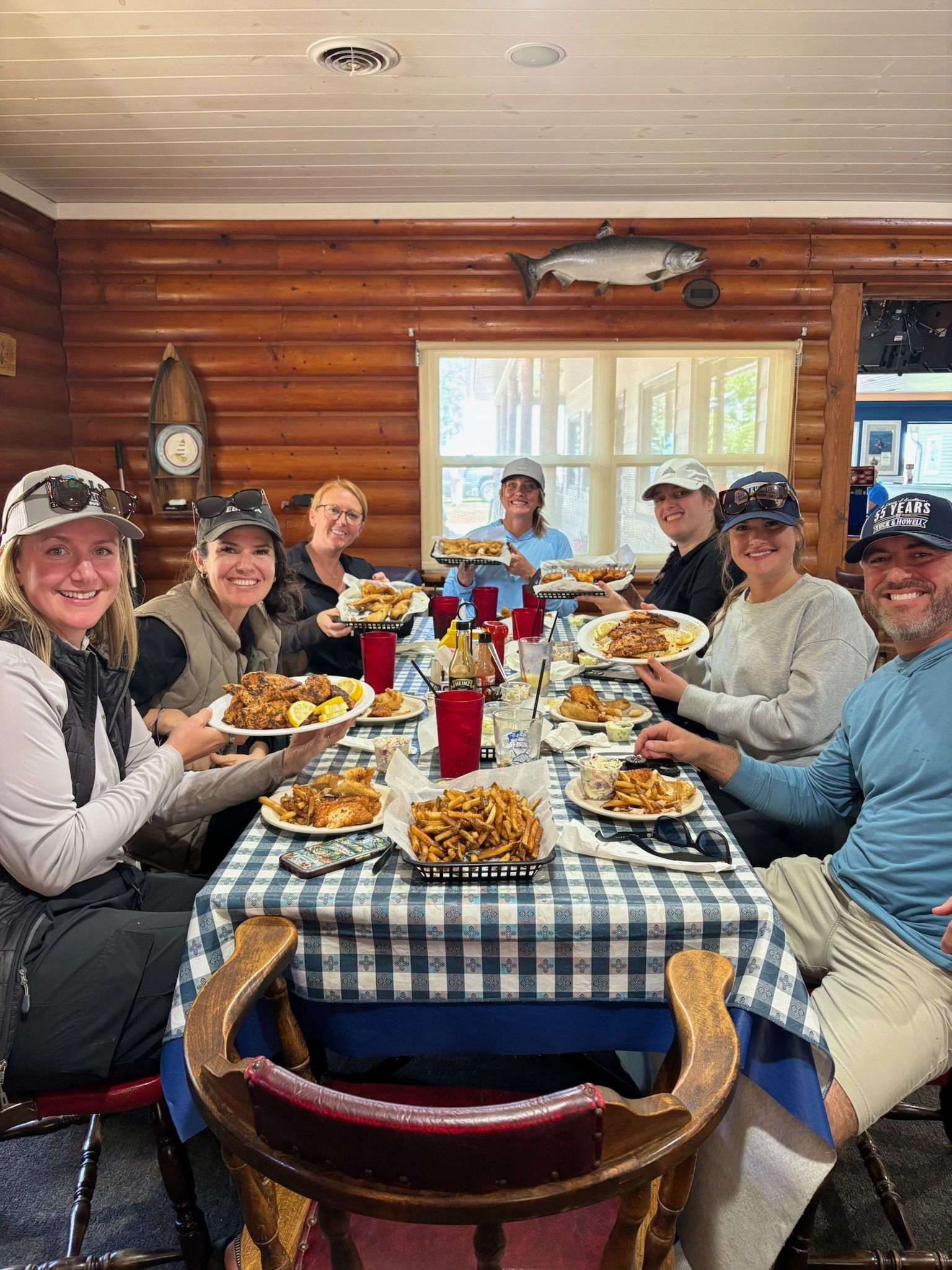 People at a table holding plates of food. Rustic log cabin dining.