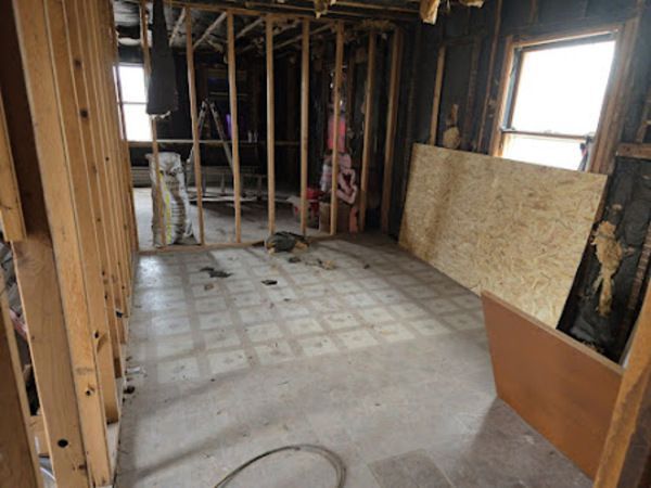 Interior of a room under construction with exposed wooden framing and floorboards.