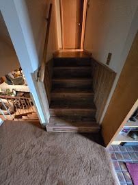 Staircase leading downward, brown steps and carpet, wooden banister.