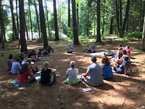 Students outside in the woods sitting in a circle