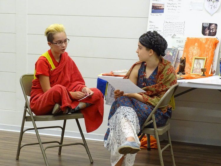 Two students dressed up in roman/greek attire in front of a project