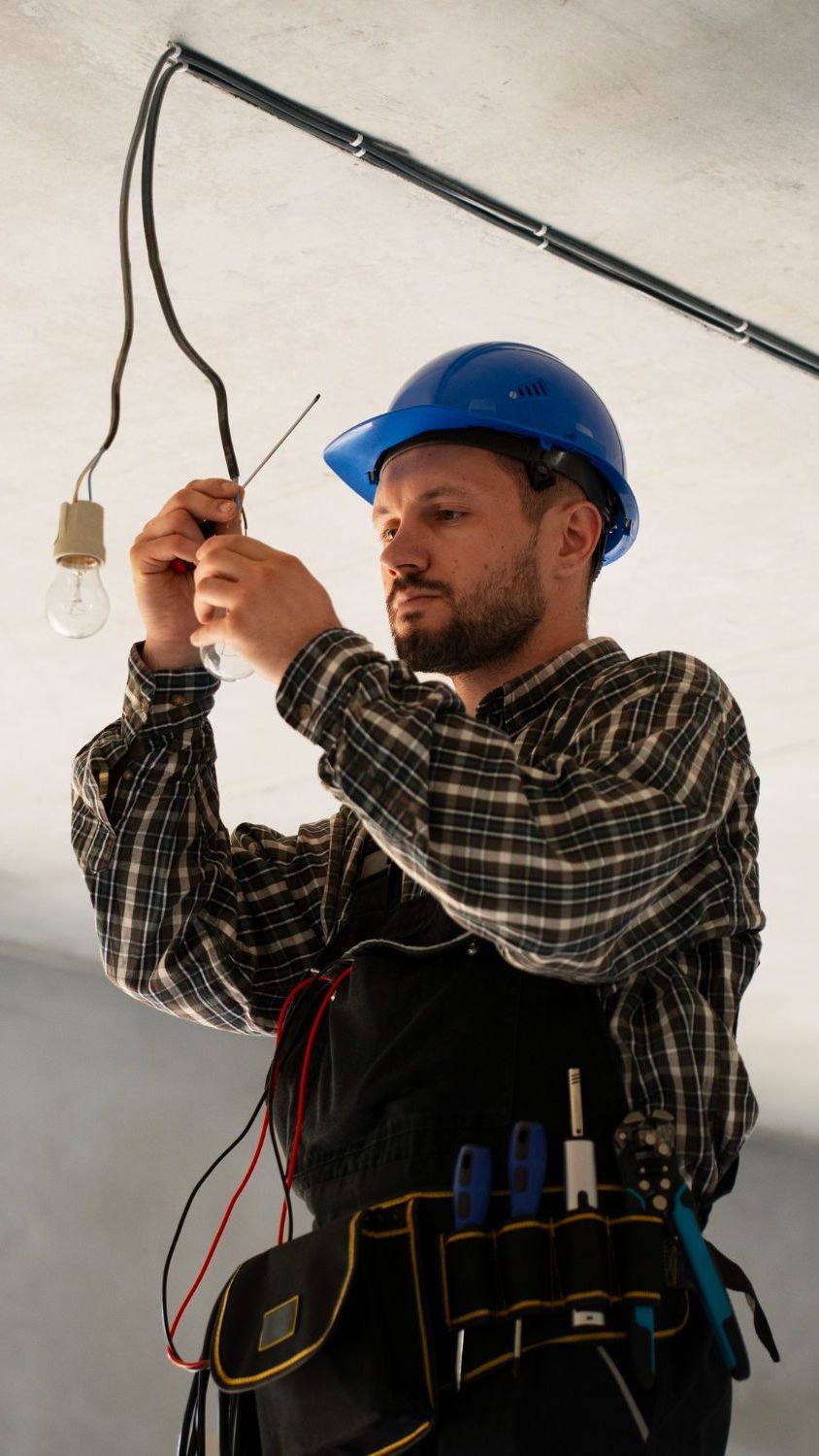A man in a hard hat is fixing a light bulb.