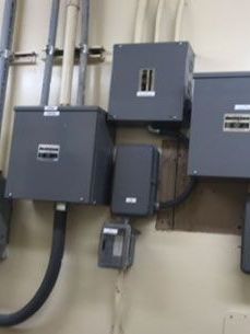 A bunch of electrical boxes are hanging on a wall.