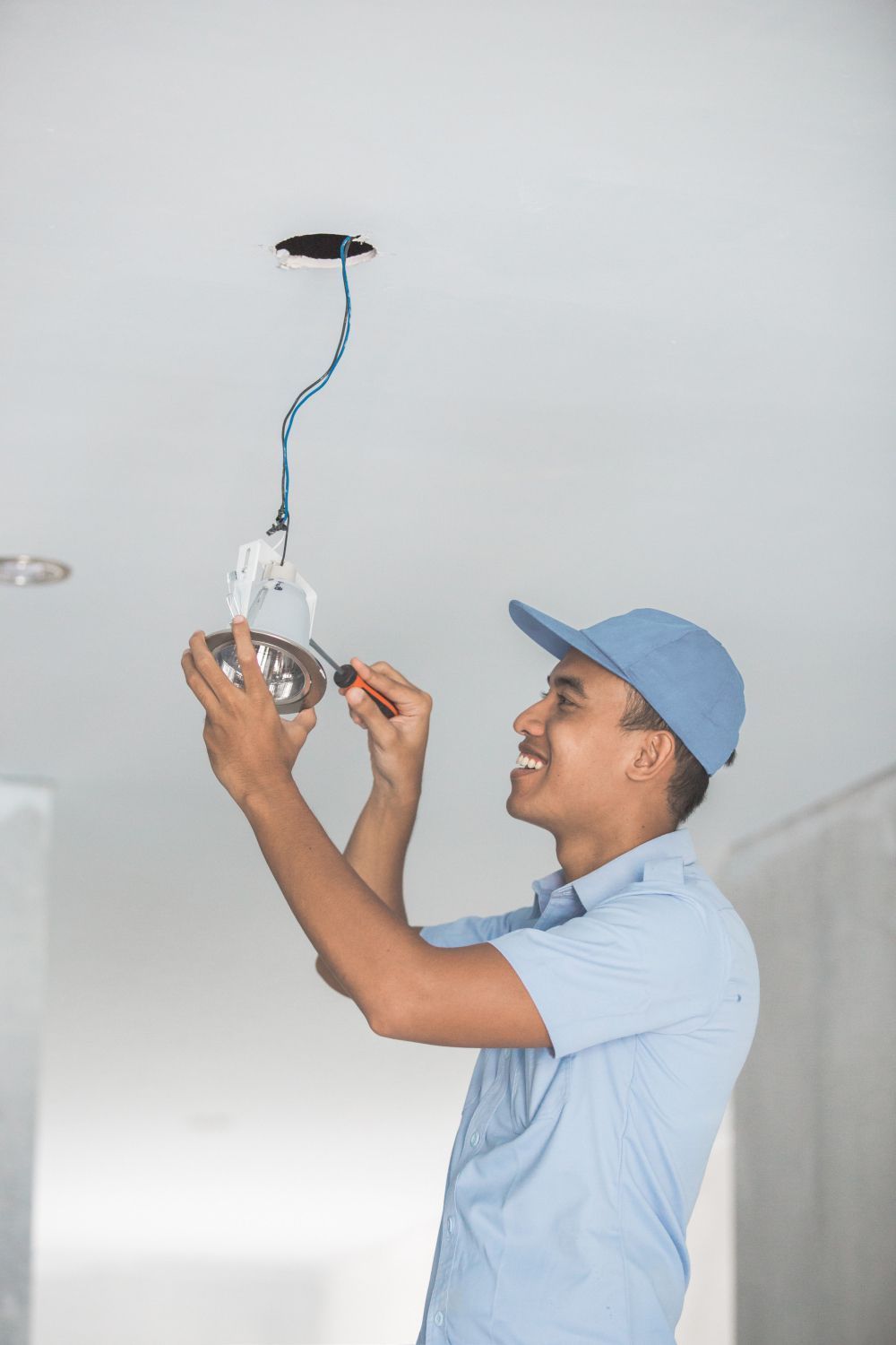 A man is installing a light bulb in a ceiling.