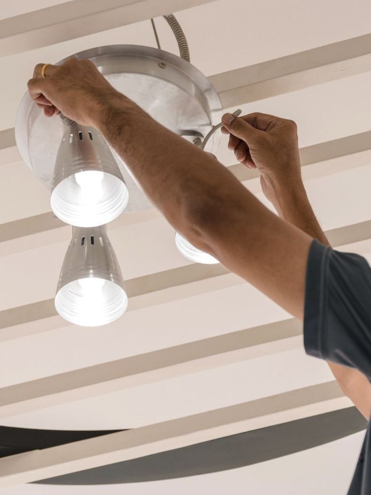 A man is installing a light fixture on the ceiling.