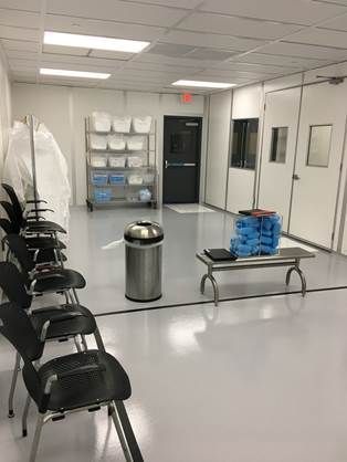 A waiting room with chairs , a trash can , and a bench.