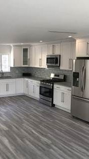 A kitchen with white cabinets , stainless steel appliances , a stove , refrigerator and microwave.