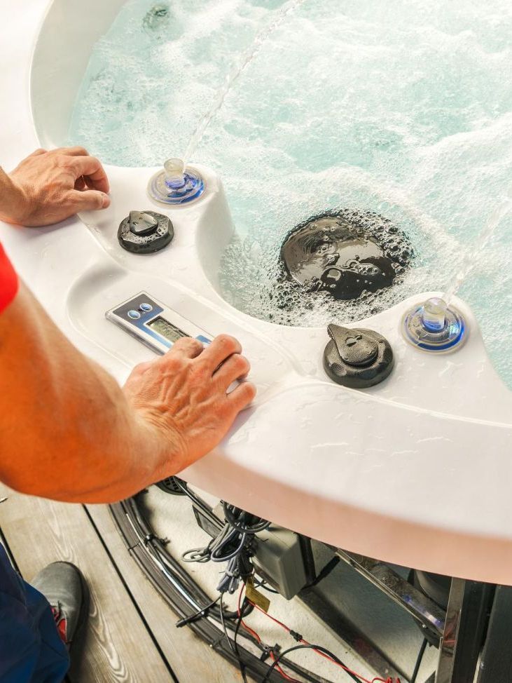 A man is working on a hot tub with a remote control.