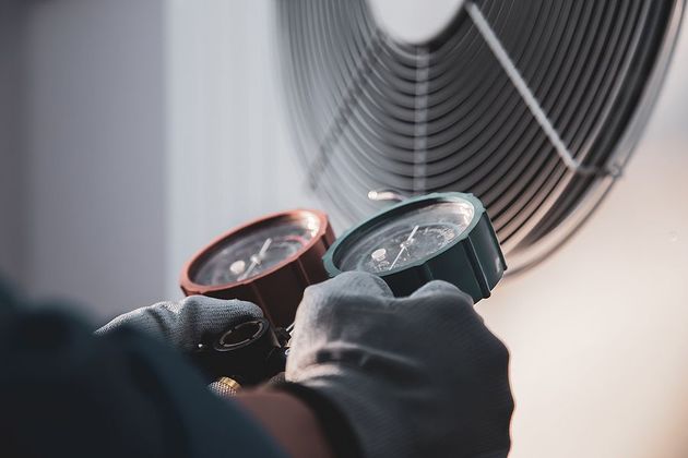 A person is holding two gauges in their hands in front of a fan.