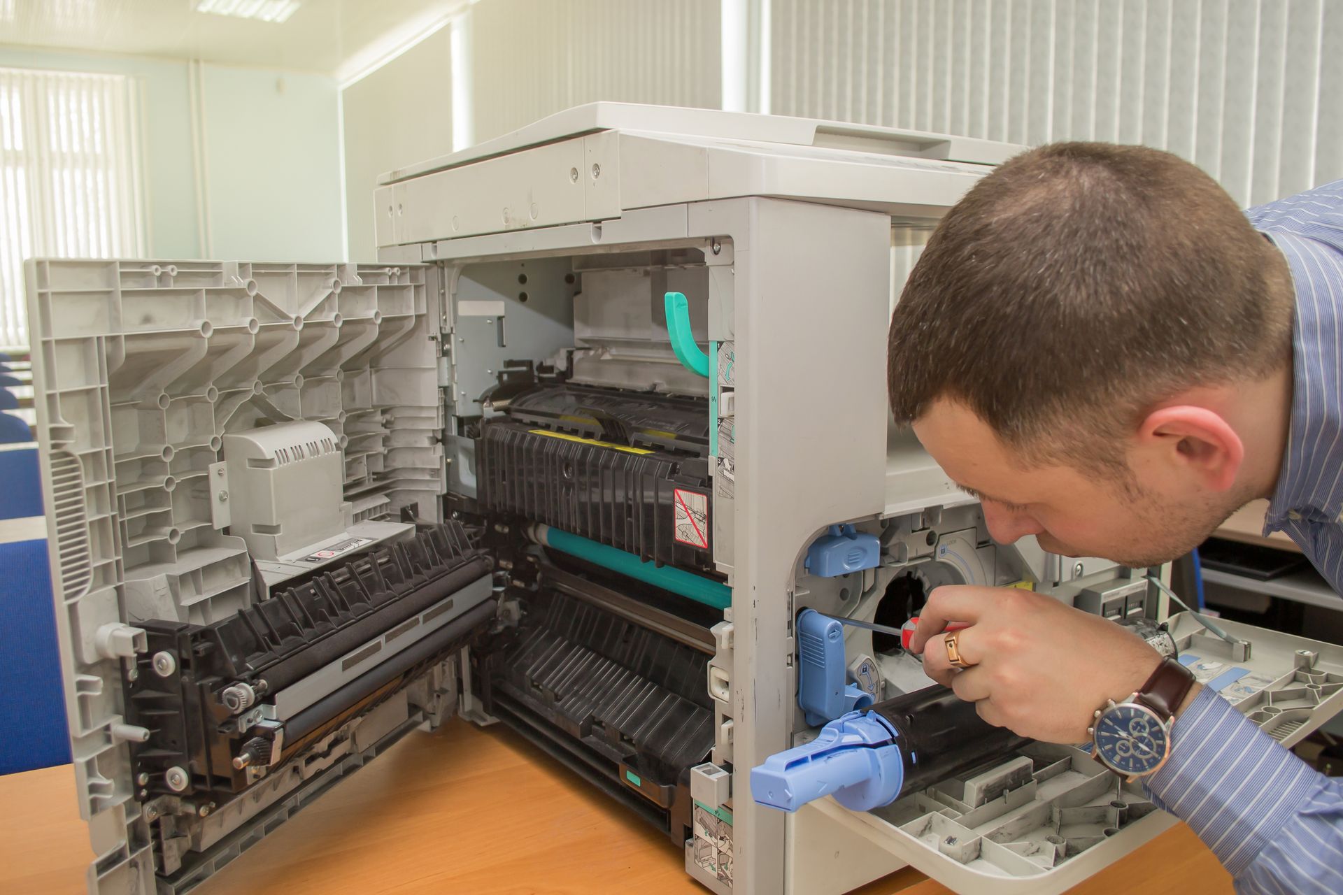 Young male technician repairing using a screwdriver and a brush digital photocopier machine. Young male technician repairing using a screwdriver and a brush digital photocopier machine.
