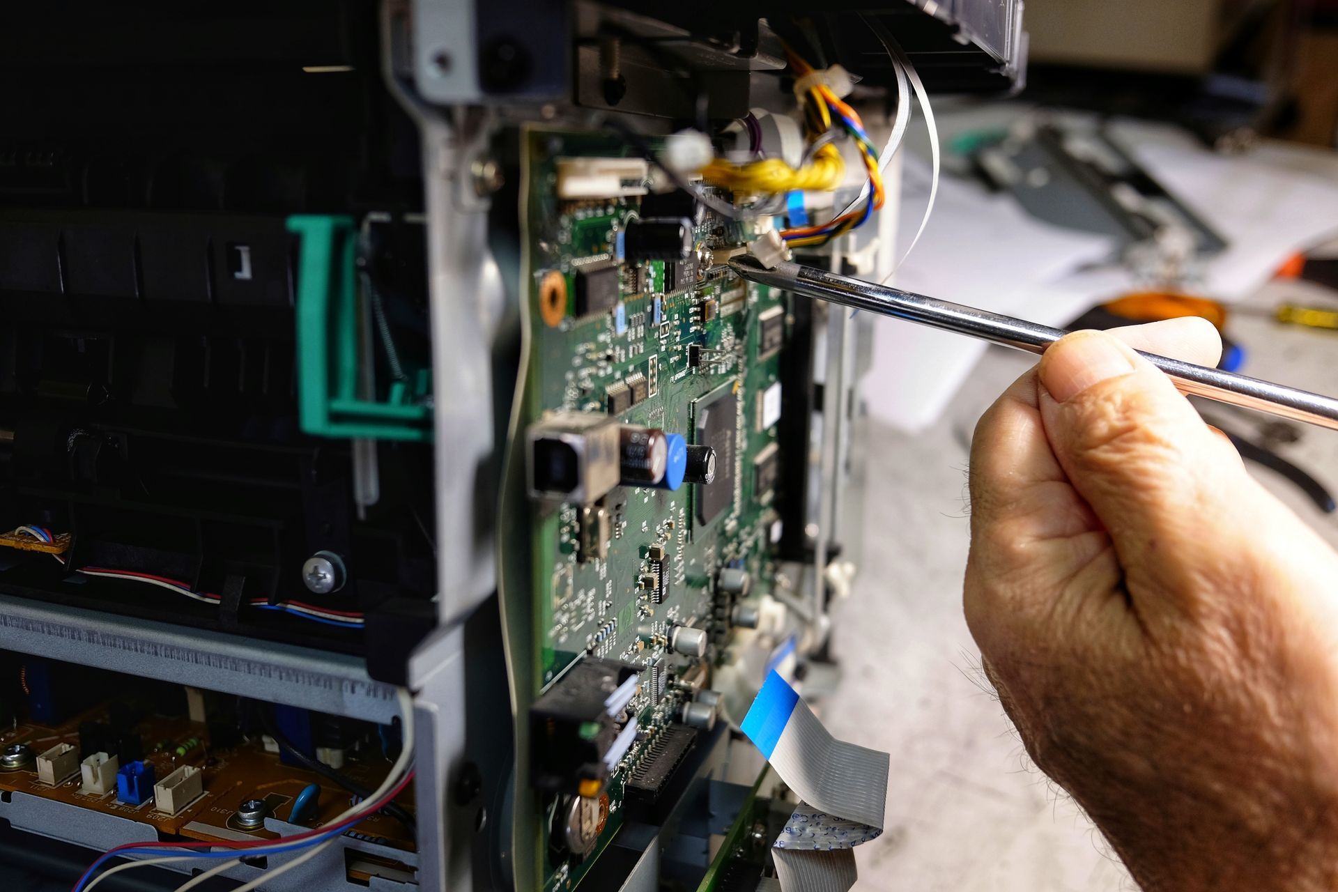 Technician repairs photocopier with screwdriver.