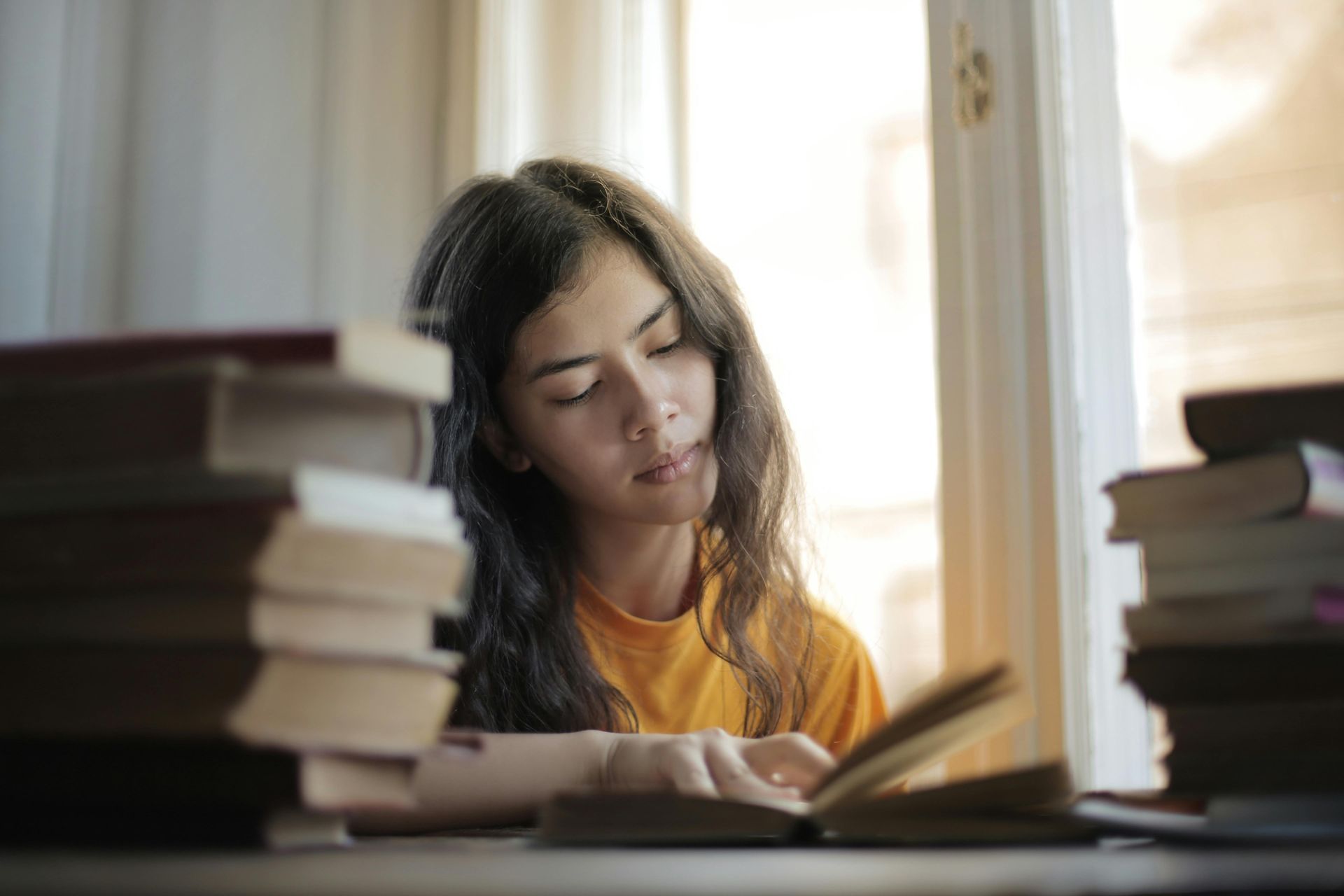 A woman reading books at her desk.