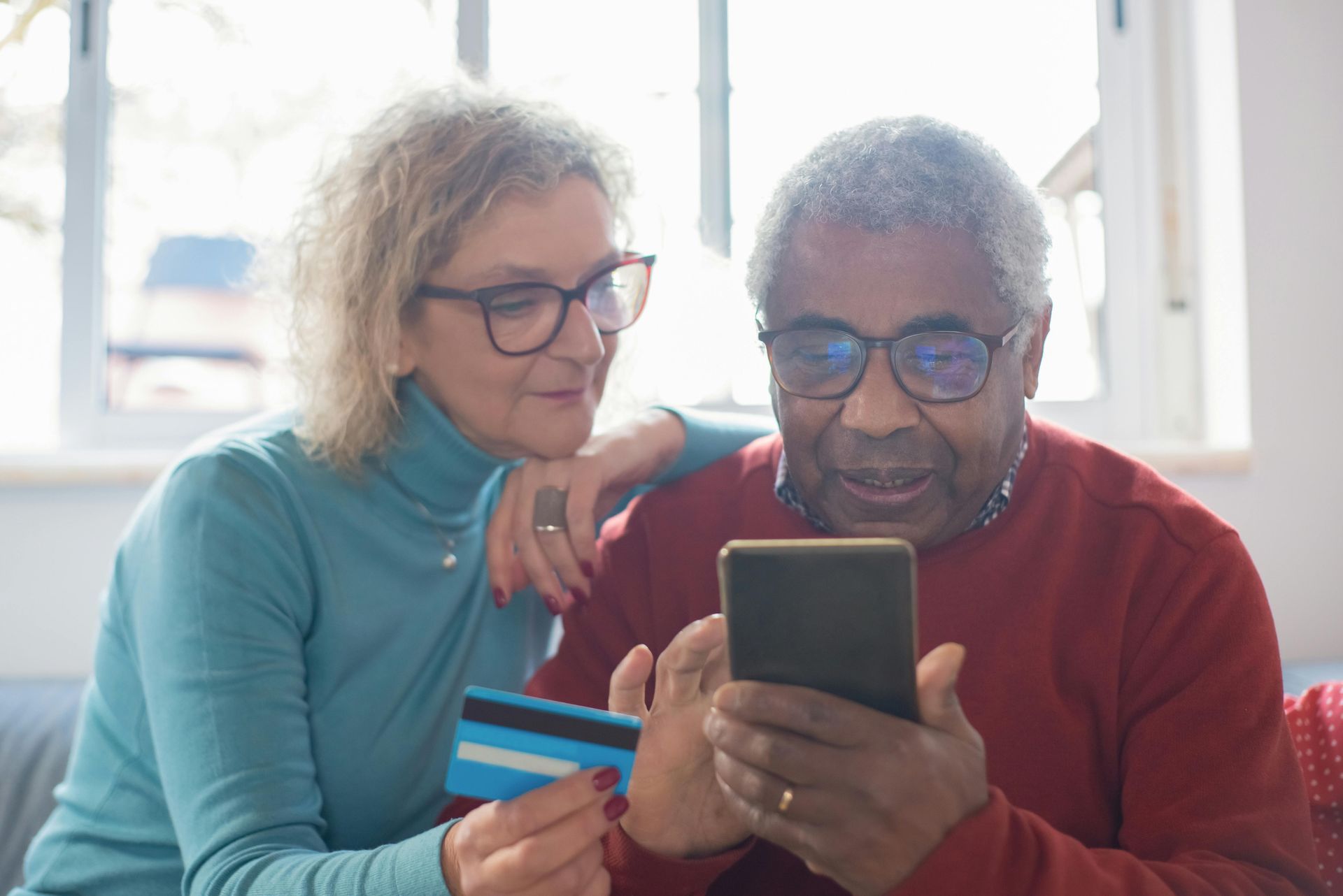 An older couple looking at their phone and credit card.