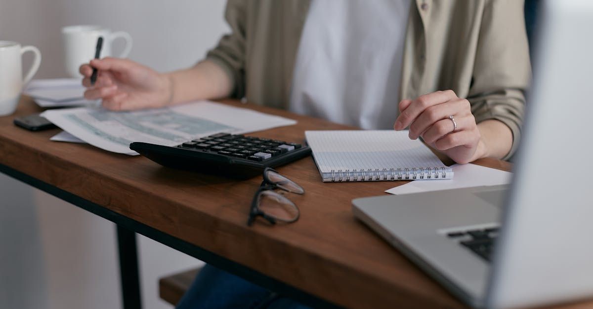 Someone at the desk with paperwork and a calculator.