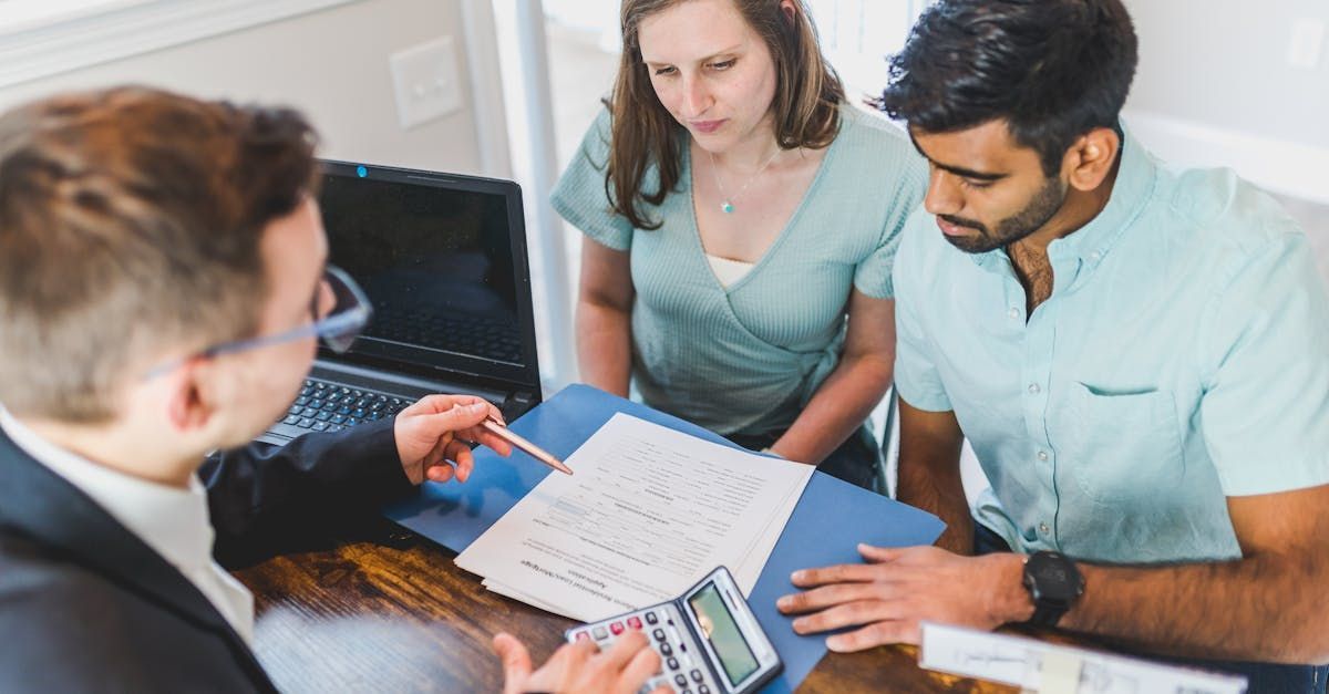 A couple looking at paper work with another individual.