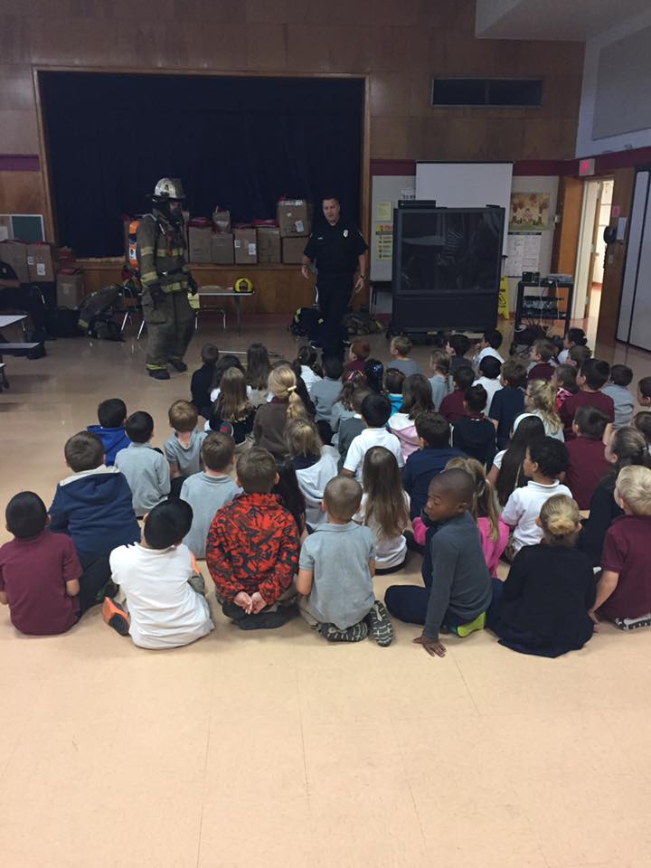 A fireman is giving a presentation to a group of children in a classroom.