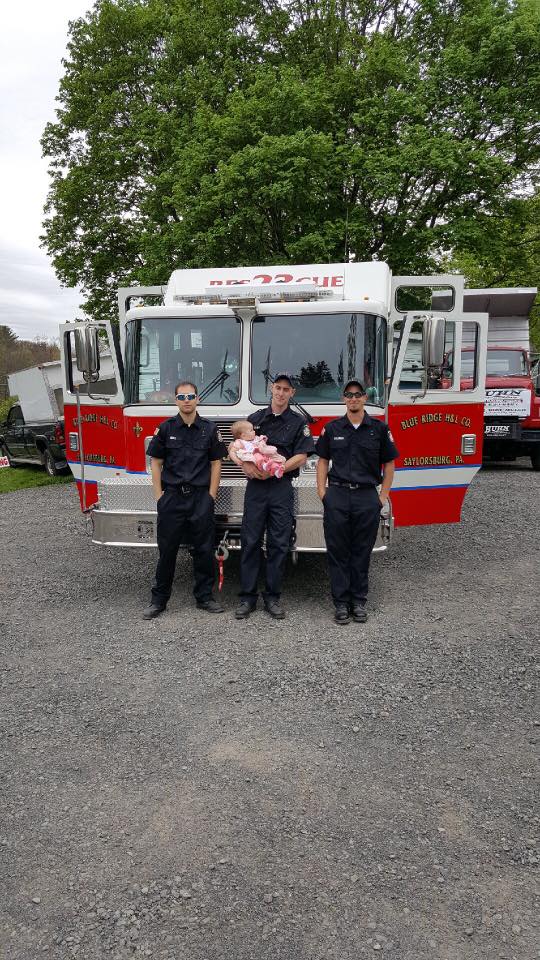 A group of firefighters are posing for a picture in front of a fire truck.