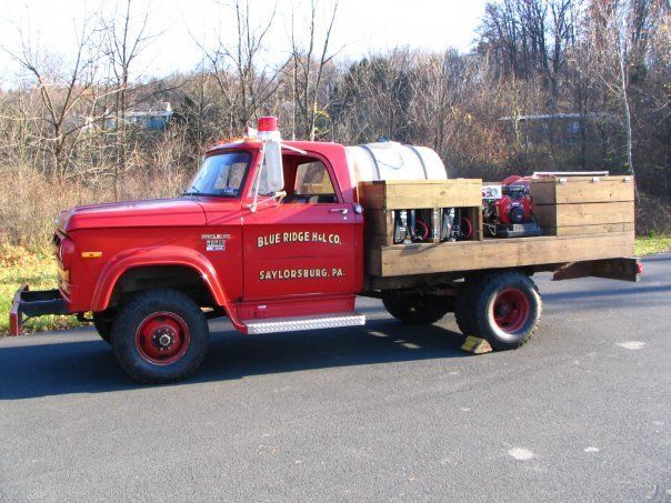A red fire truck with a wooden box on the back is parked on the side of the road