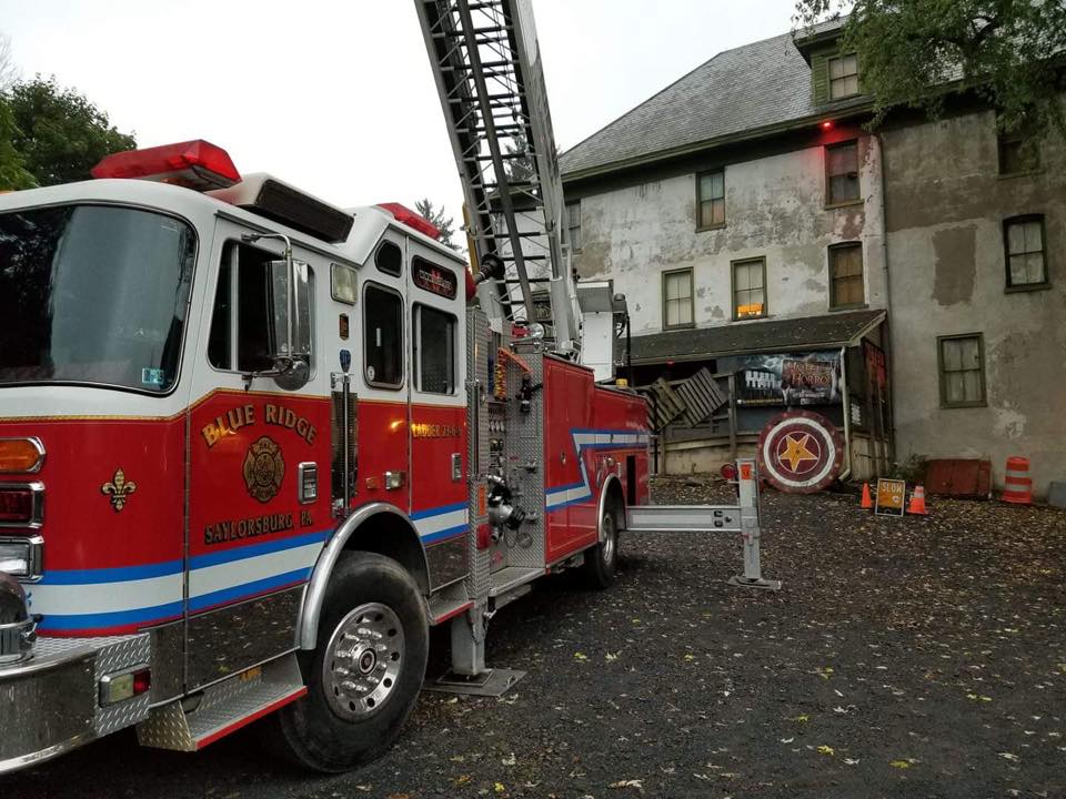 A red and white fire truck with a ladder is parked in front of a building