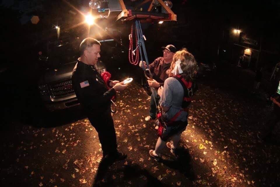 A group of people are standing in a dark room talking to each other