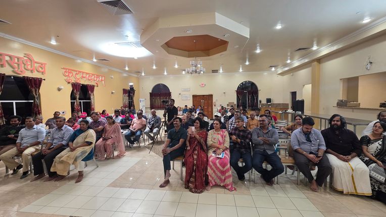 Guests seated at a decorated indoor banquet hall, facing the camera at a formal event.