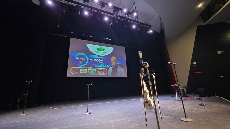 Empty stage with spotlights and a large screen showing a colorful presentation backdrop