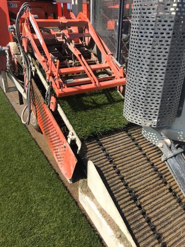 A machine is cutting artificial grass on a soccer field.