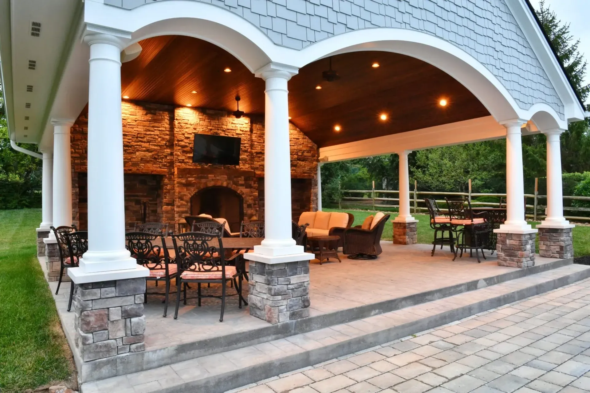 A covered patio with a fireplace and tables and chairs