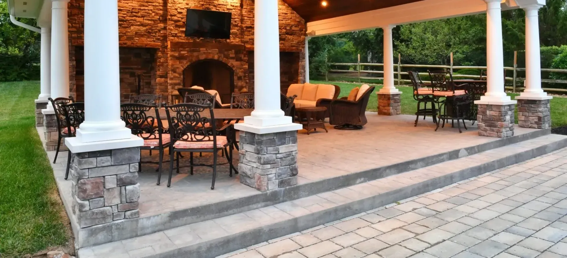 A covered patio with a fireplace and tables and chairs