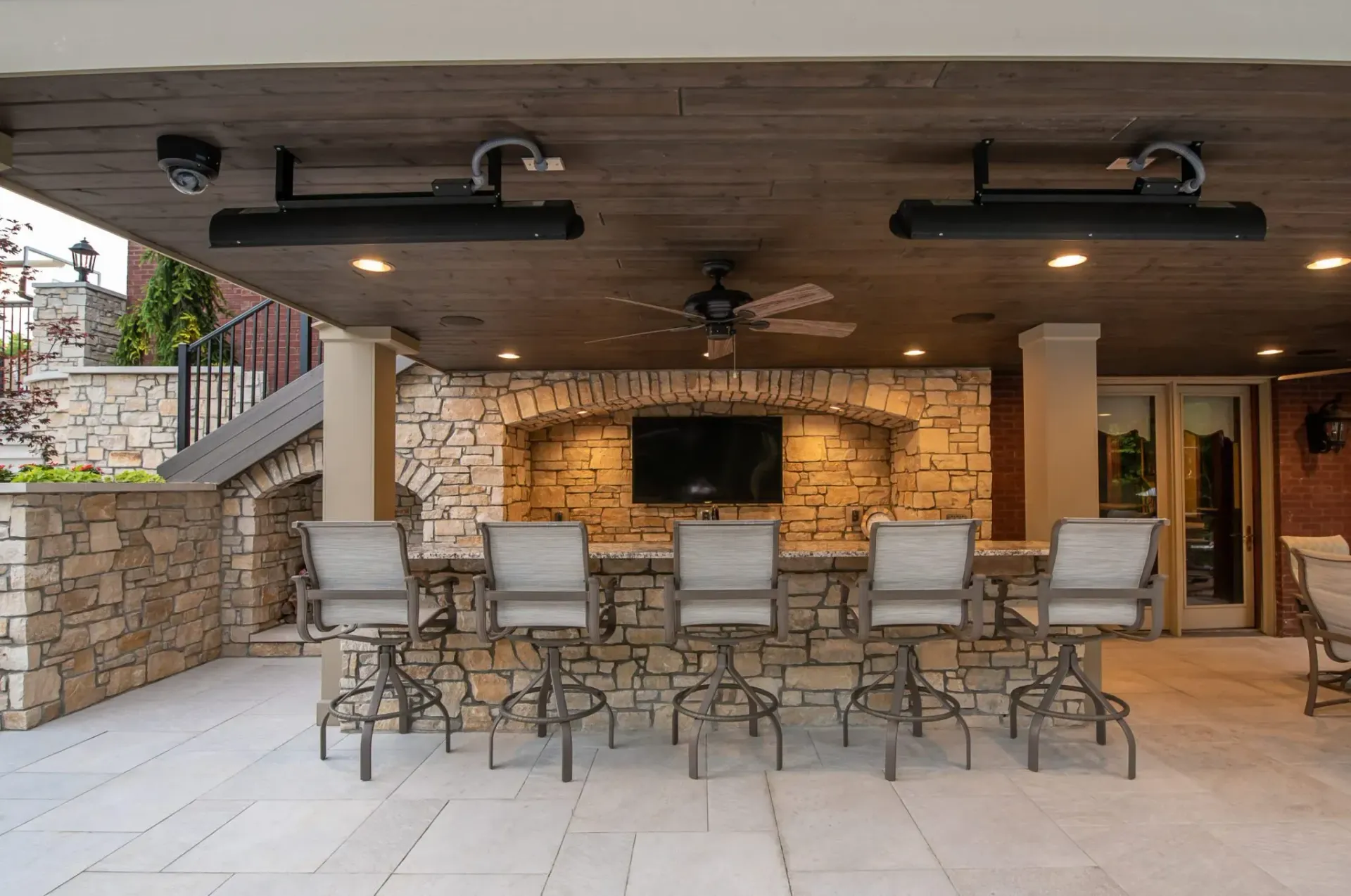 A patio with tables and chairs and a television installed by Reston Construction.