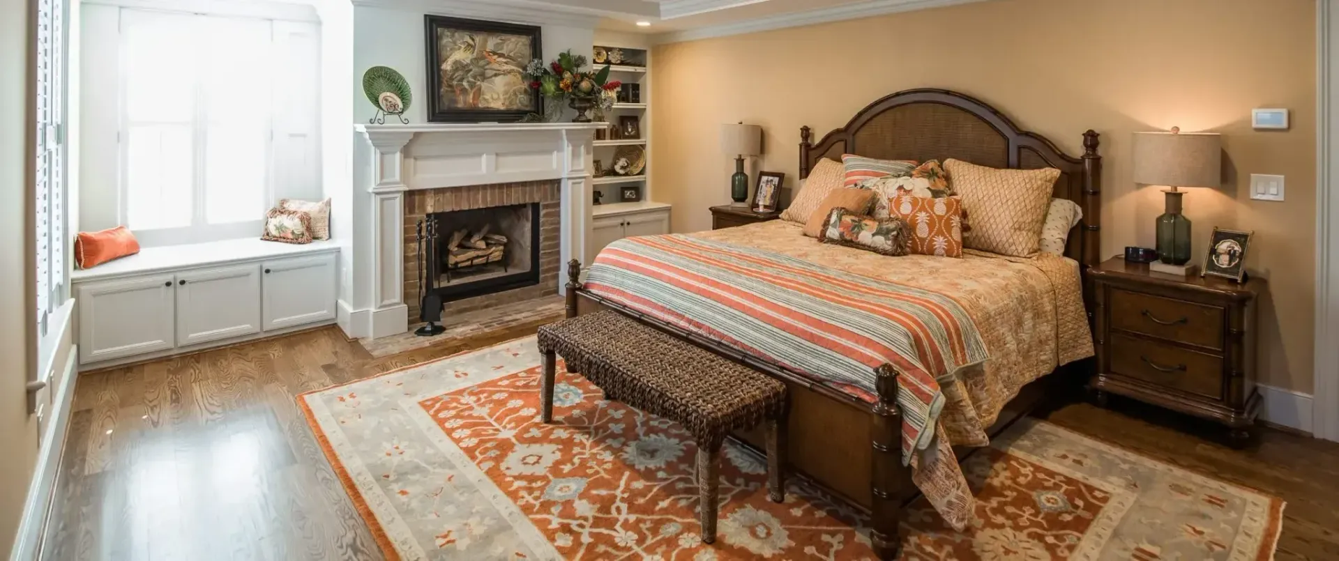 A bedroom with a bed , nightstand , fireplace and rug.
