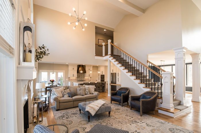 A living room with a couch , chairs , stairs and a fireplace.
