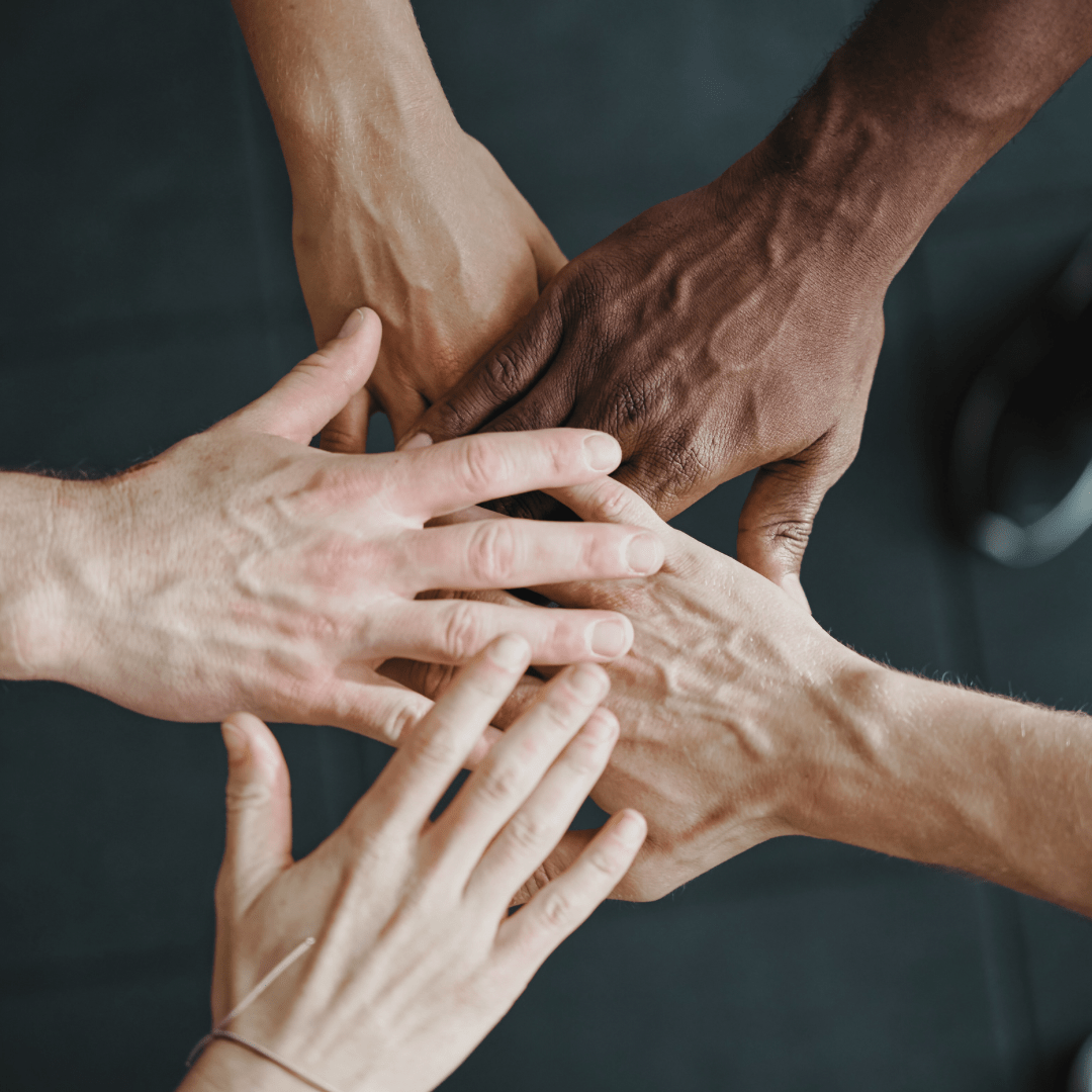 A group of people are putting their hands together in a circle.