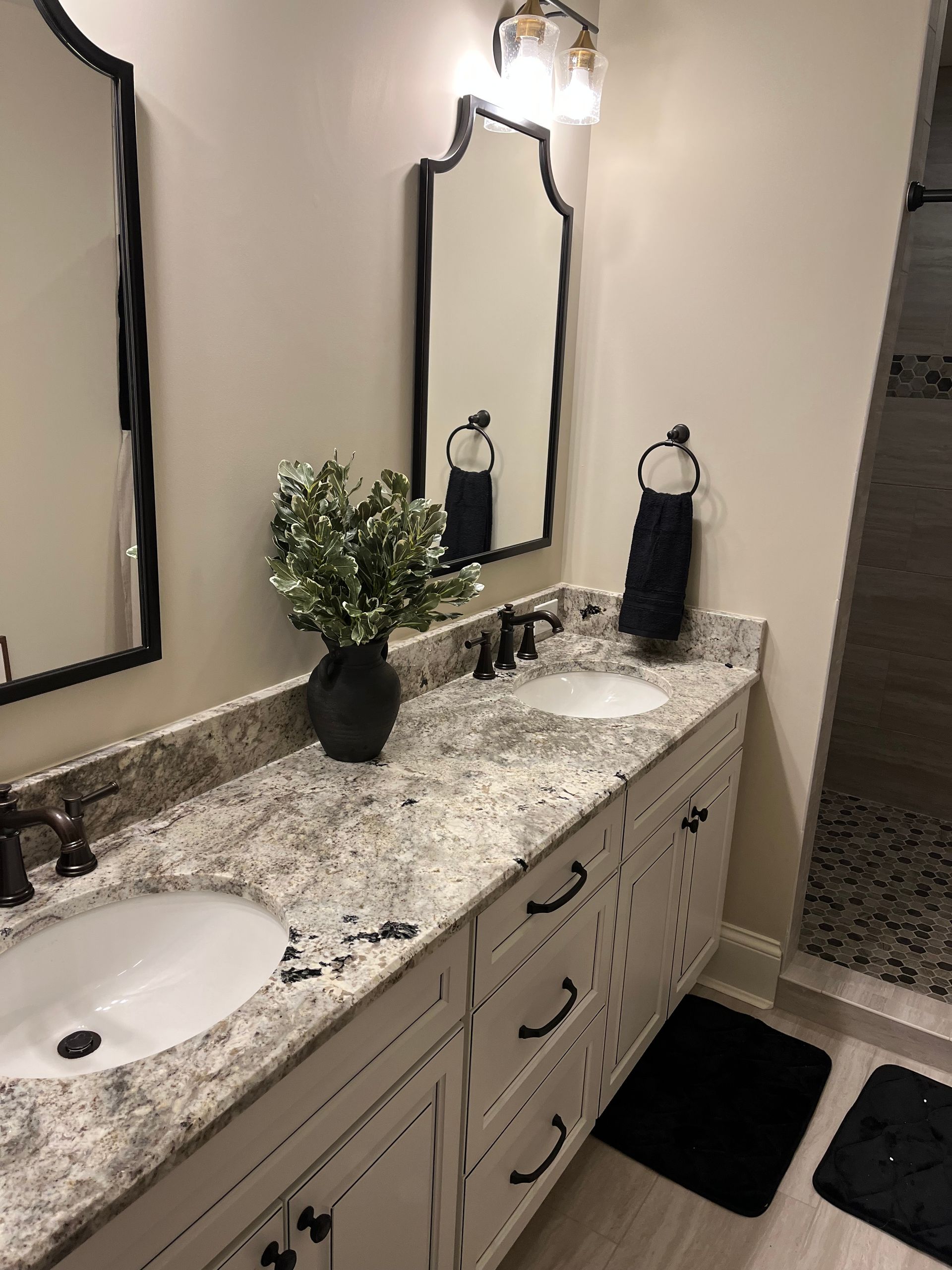 A bathroom with two sinks and two mirrors Installed by Reston Construction.