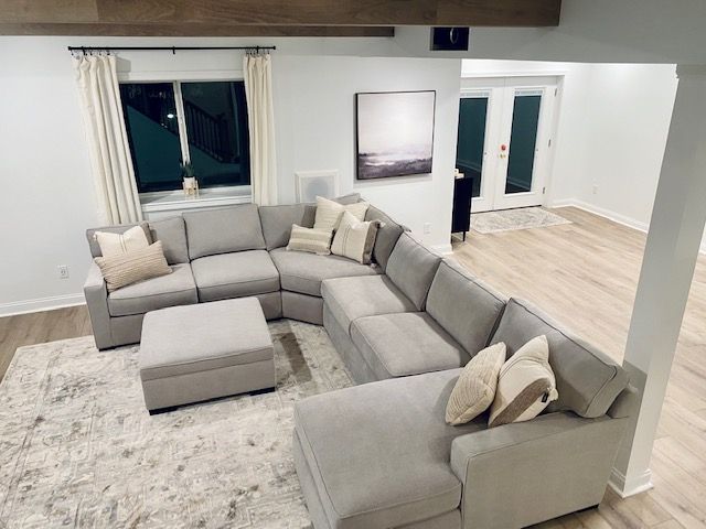 A living room with a large sectional couch and ottoman Installed by Reston Construction.