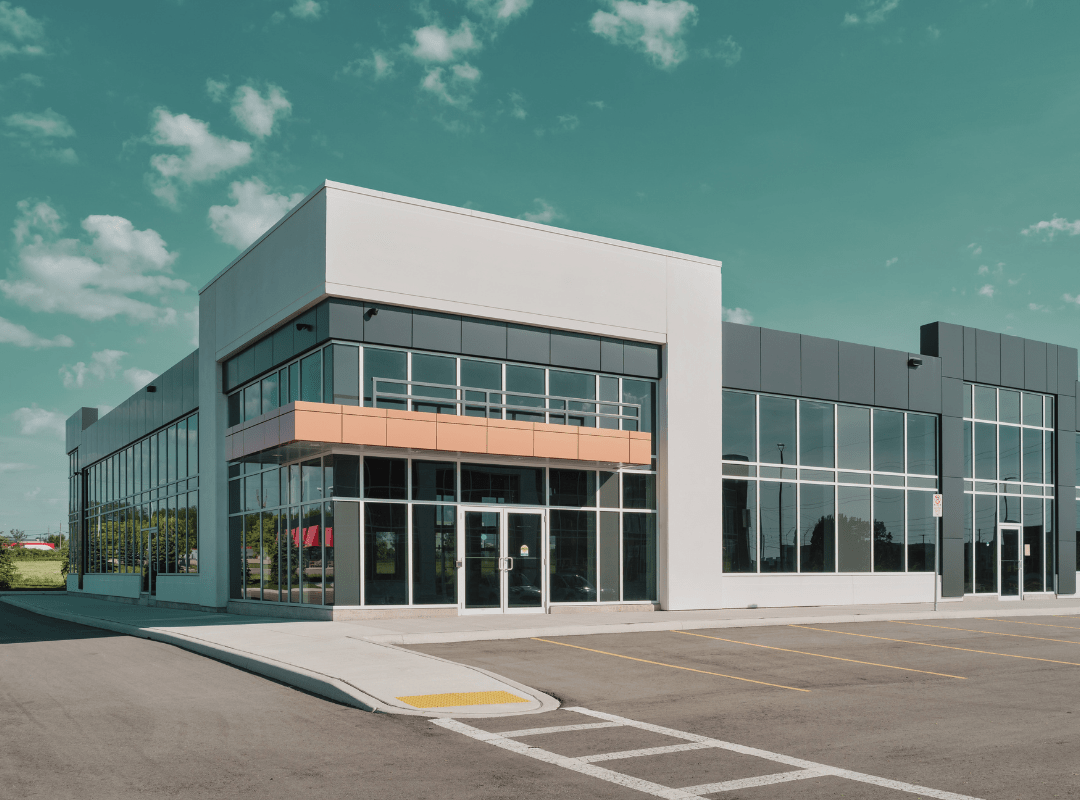 A large building with a lot of windows and a parking lot in front of it.