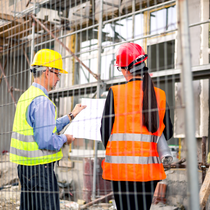 A man and a woman are standing next to each other on a construction site.