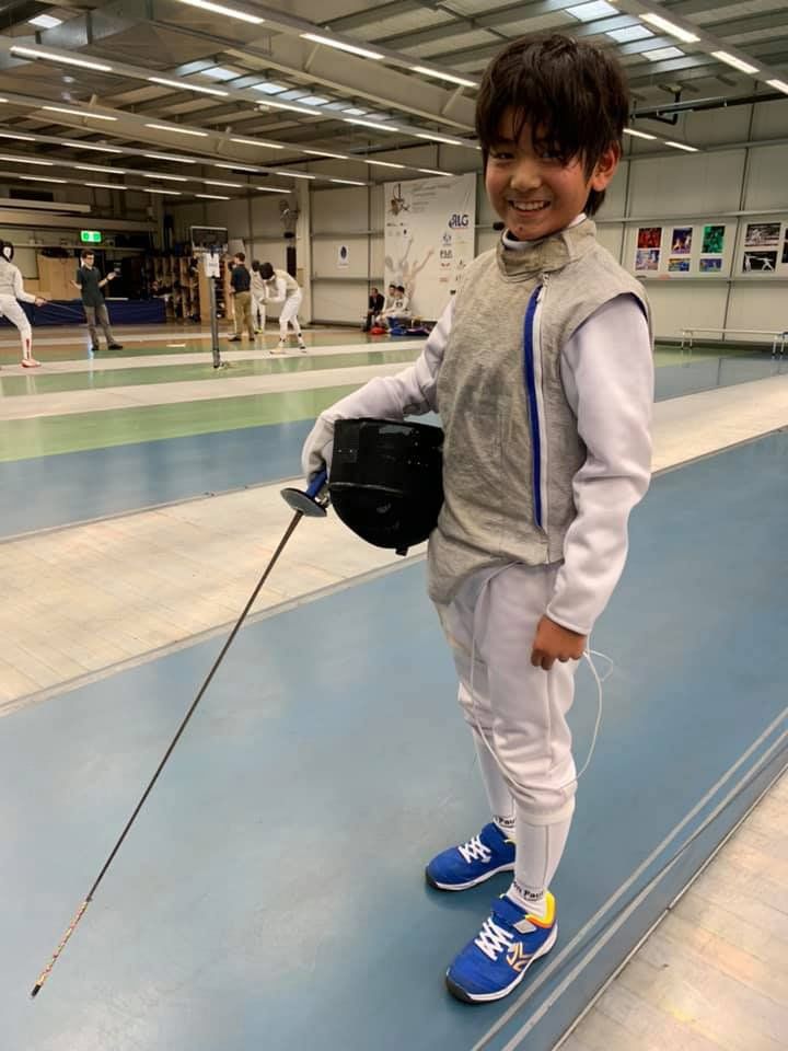 child in white on fencing mat
