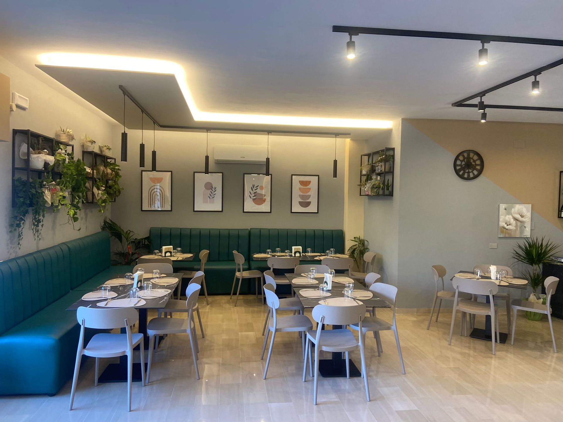 Interno di un ristorante moderno con sedute color verde acqua, pareti neutre e opere d'arte decorative.