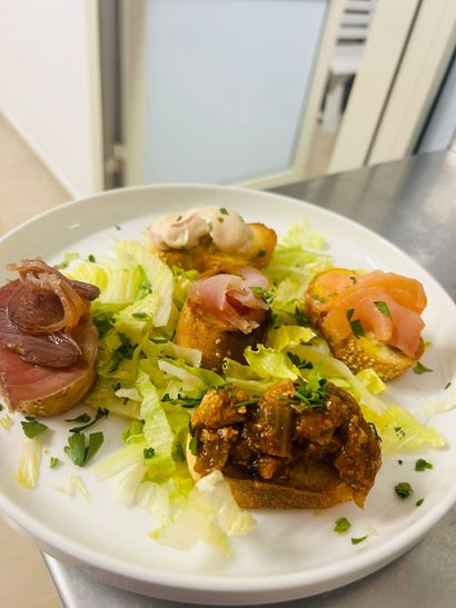 Un piatto di antipasti: pane tostato condito con vari ingredienti e guarnito con lattuga.
