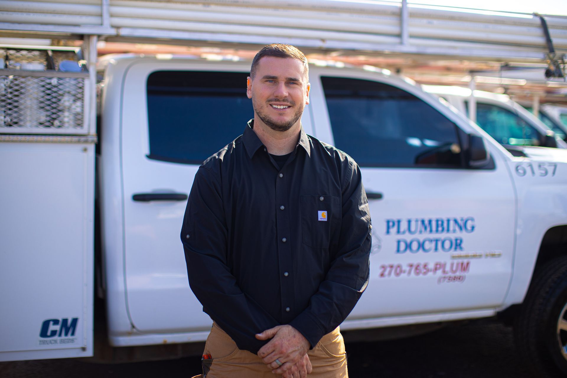 Man in work clothes standing in front of a Plumbing Doctor truck.