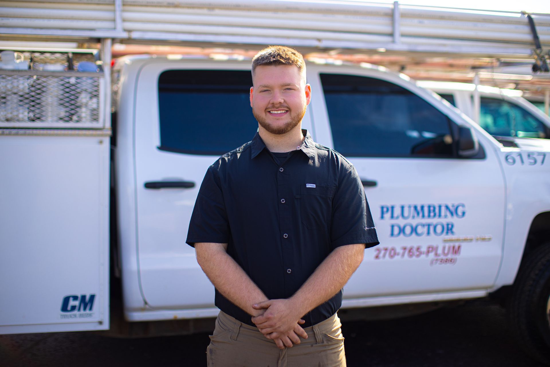 Plumber in navy shirt standing in front of Plumbing Doctor truck.