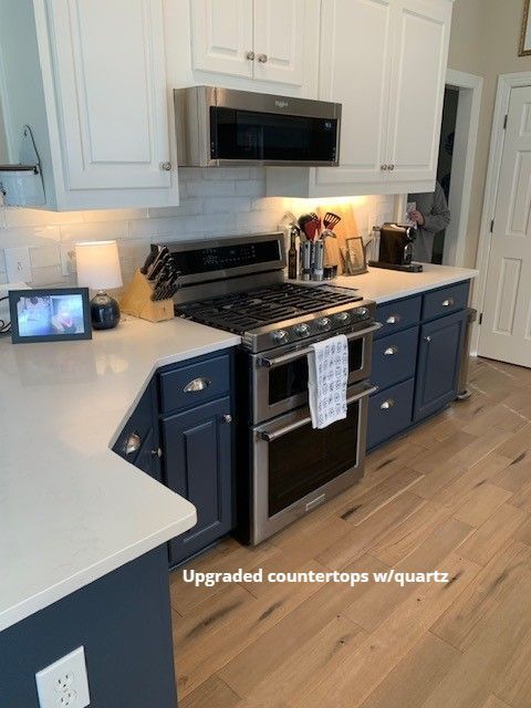 Kitchen with white quartz countertops, blue cabinets, stainless steel appliances, and white upper cabinets.