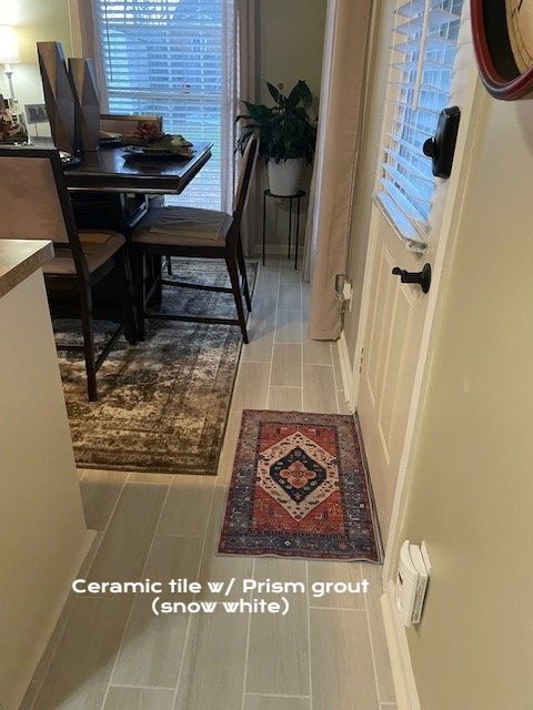 Ceramic tile floor with rug in a dining area. Table and chairs with window and door.