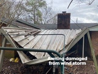 Damaged awning, bent and torn by a wind storm, in front of a house.