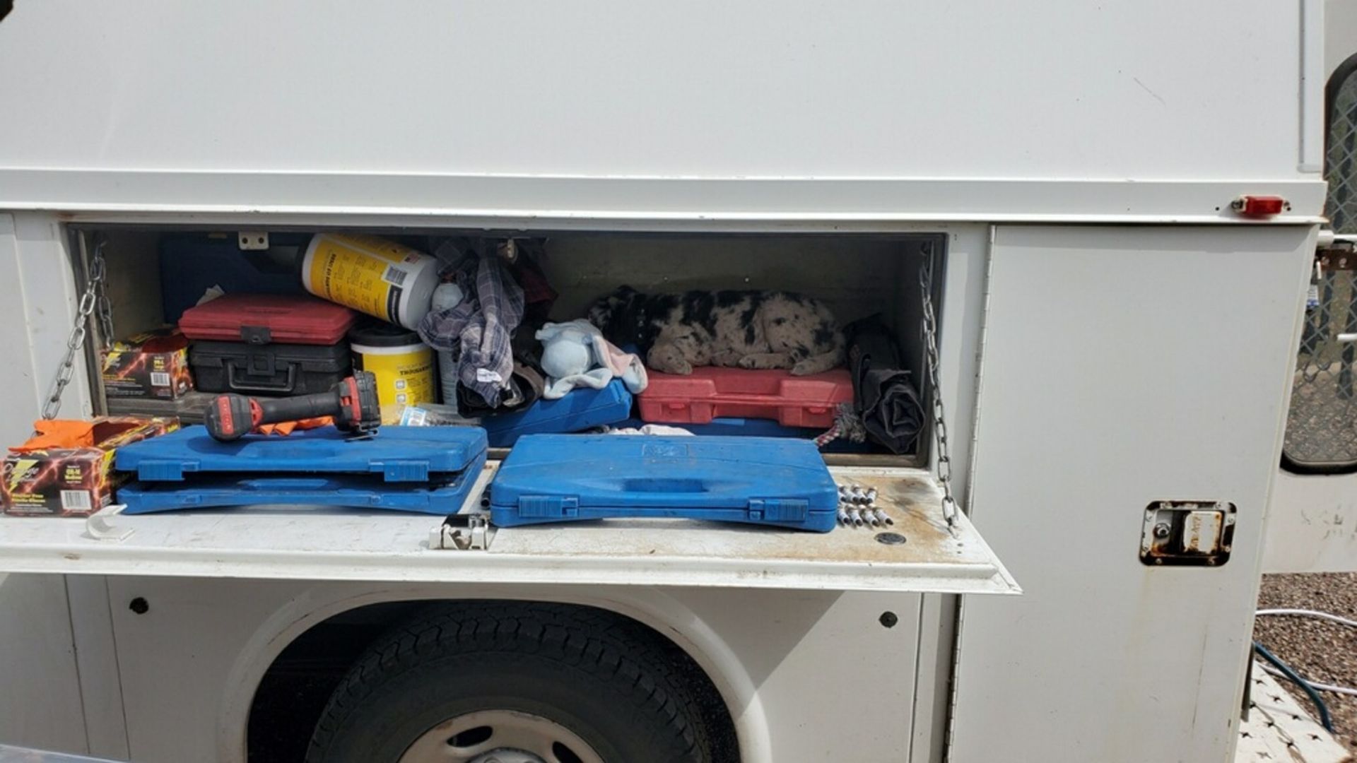 The back of a white truck is filled with tools.