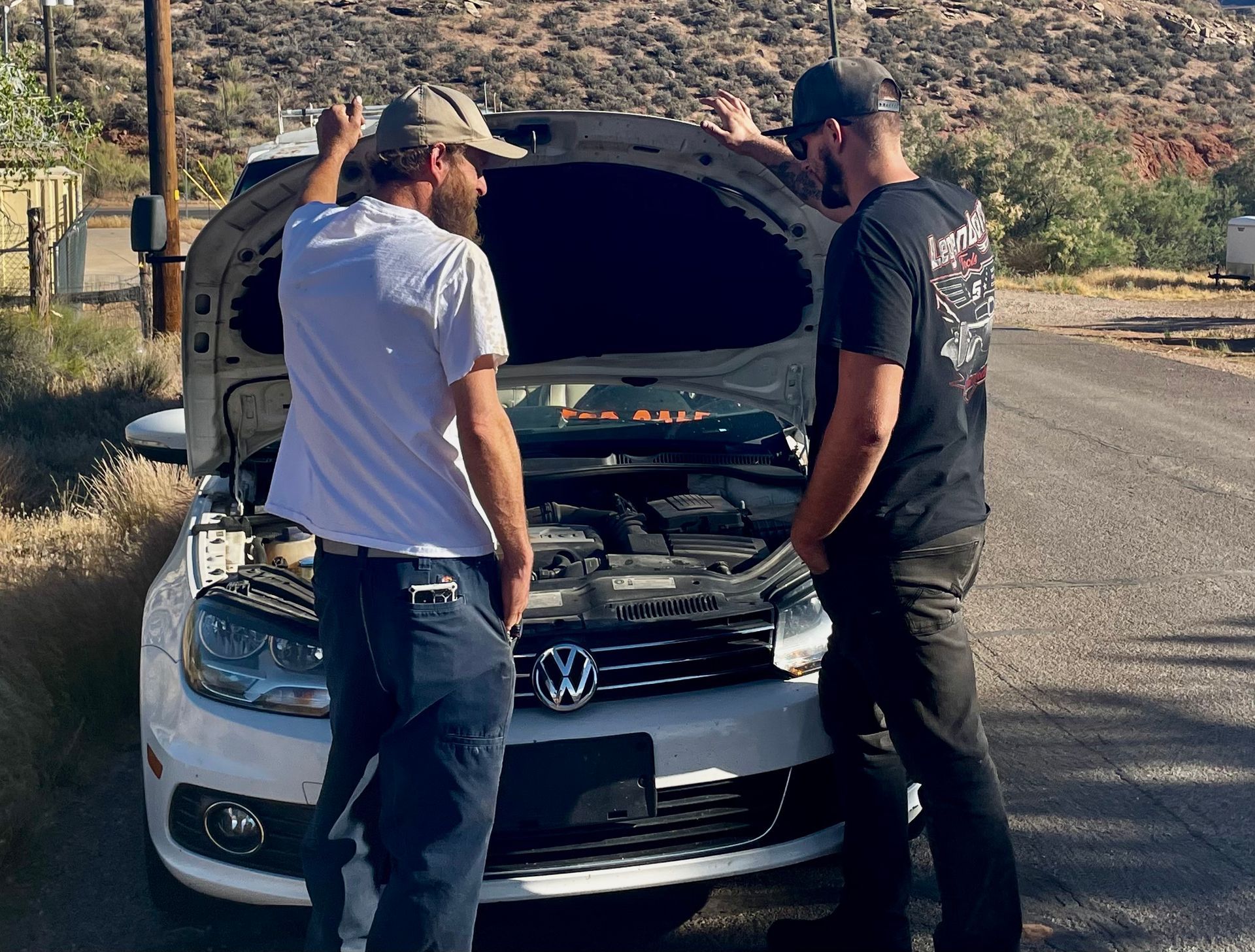 Two men are looking under the hood of a volkswagen