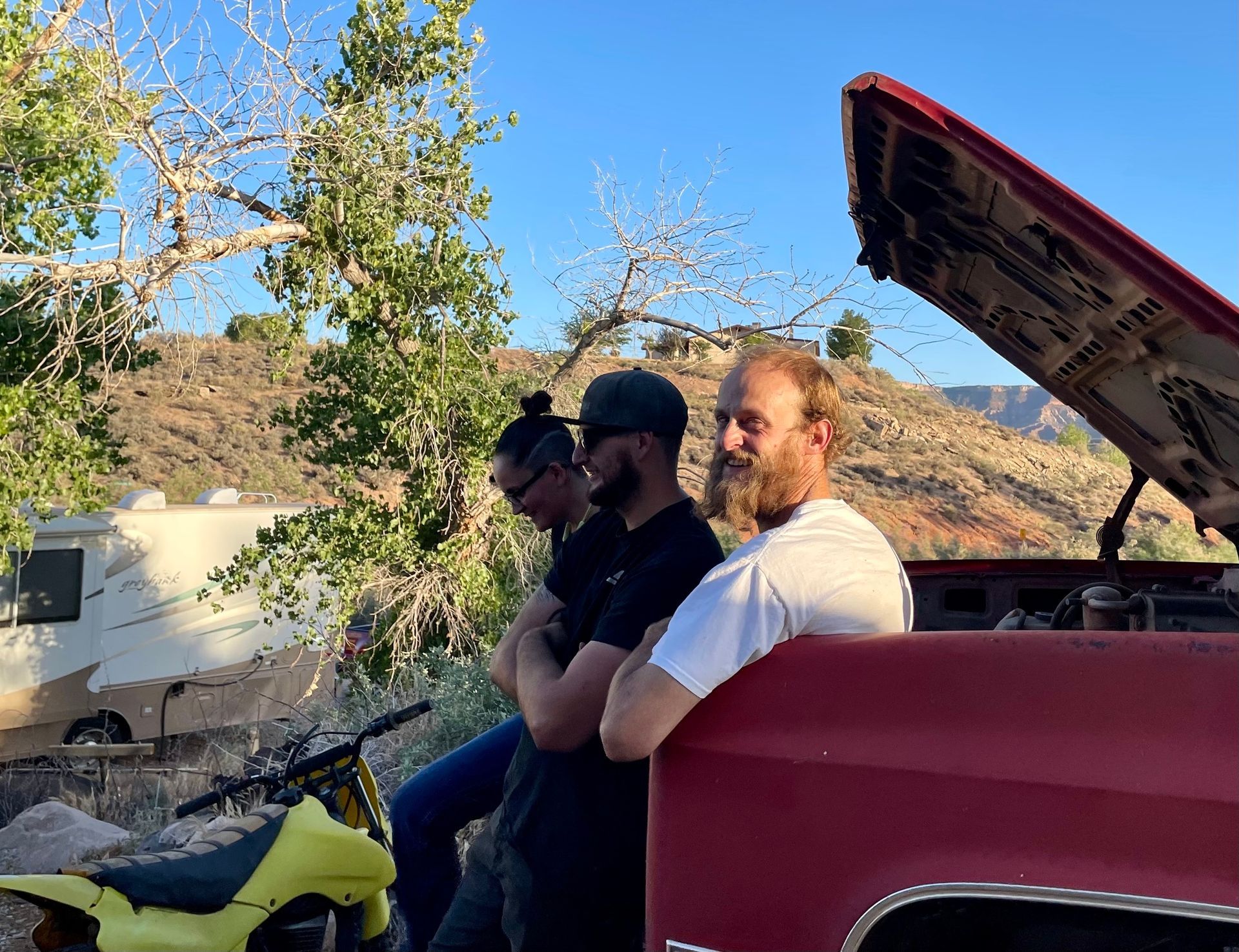 Three men are sitting in the back of a red truck.