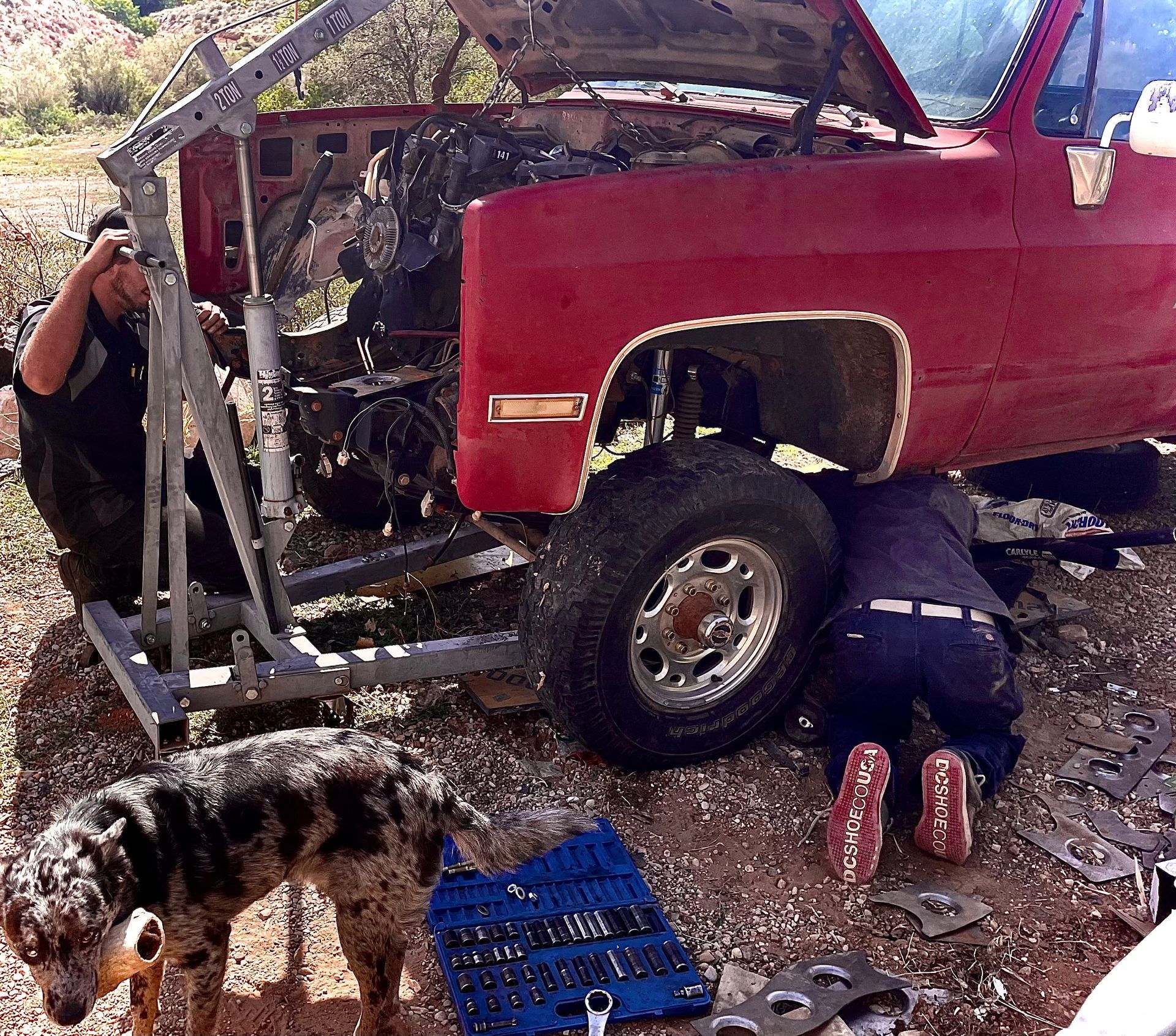 A man is working under the hood of a red truck